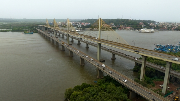 Aerial view of Atal Setu Goa a cable stayed bridge spanning the Mandovi River with traffic flowing across its lanes surrounded by lush riverbanks and urban development in Panaji Goa India.