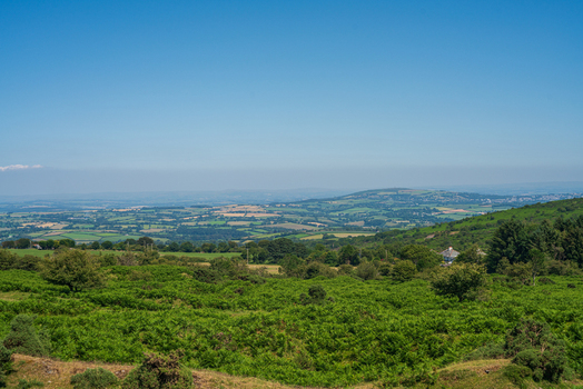 View of the Cheesewring landmark surrounded by rolling green hills and rural countryside in Minions Cornwall United Kingdom. View of the Cheesewring landmark surrounded by rolling green hills and rural countryside in Minions Cornwall United Kingdom.