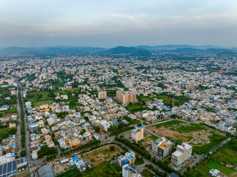 Aerial view of dense residential buildings and urban landscape with green patches and distant hills under a soft sky in Udaipur Rajasthan India. Aerial view of dense residential buildings and urban landscape with green patches and distant hills under a soft sky in Udaipur Rajasthan India.