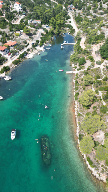 Aerial view of the shipwreck in the turquoise waters of Necujam bay with people swimming and small boats nearby Necujam Split Dalmatia County Croatia. Aerial view of the shipwreck in the turquoise waters of Necujam bay with people swimming and small boats nearby Necujam Split Dalmatia County Croatia.