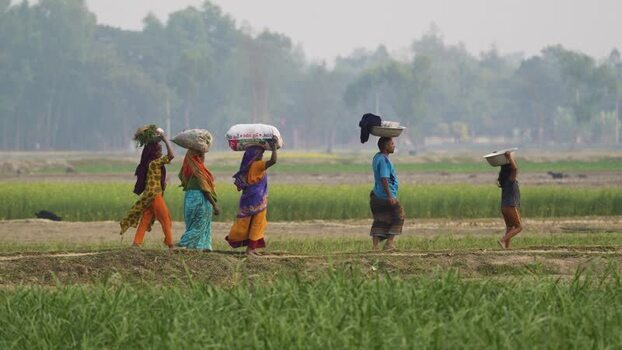 View of people carrying loads on their heads in Bogura Bangladesh.