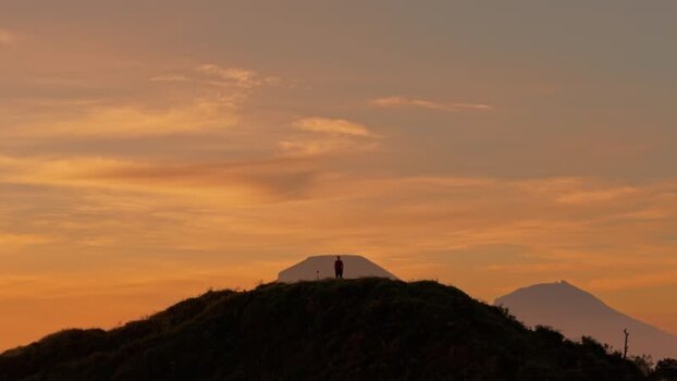 Aerial view of a person silhouette on a hill at sunset Indonesia.