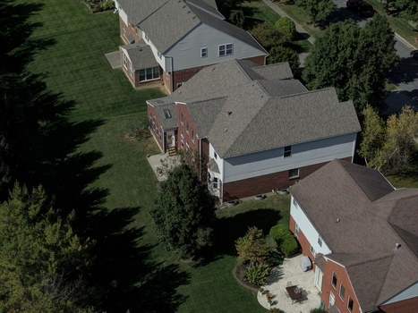Aerial view of suburban houses with brick and siding exteriors green lawns and mature trees in a residential neighborhood in Mason Ohio United States.