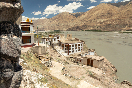View of Charasa Gonpa monastery perched on a rocky cliff overlooking the river valley with arid mountains in the background in Charasa Ladakh India.