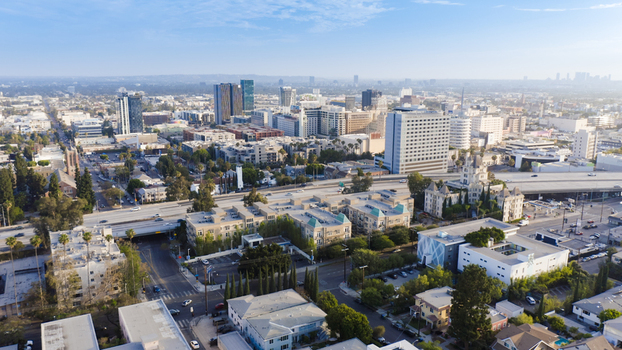 Aerial view of the urban landscape featuring modern high rise buildings residential blocks and a highway overpass under a clear blue sky in Los Angeles California United States.