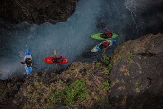 View of kayakers paddling through the turquoise waters of the Rio Manso canyon surrounded by steep rocky cliffs and lush vegetation San Carlos de Bariloche Rio Negro Argentina. View of kayakers paddling through the turquoise waters of the Rio Manso canyon surrounded by steep rocky cliffs and lush vegetation San Carlos de Bariloche Rio Negro Argentina.