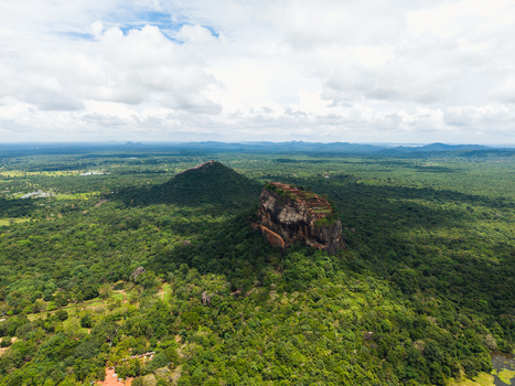 Aerial view of Sigiriya Lion Rock fortress surrounded by dense tropical jungle and lush greenery under a cloudy sky Sigiriya Central Province Sri Lanka. Aerial view of Sigiriya Lion Rock fortress surrounded by dense tropical jungle and lush greenery under a cloudy sky Sigiriya Central Province Sri Lanka.