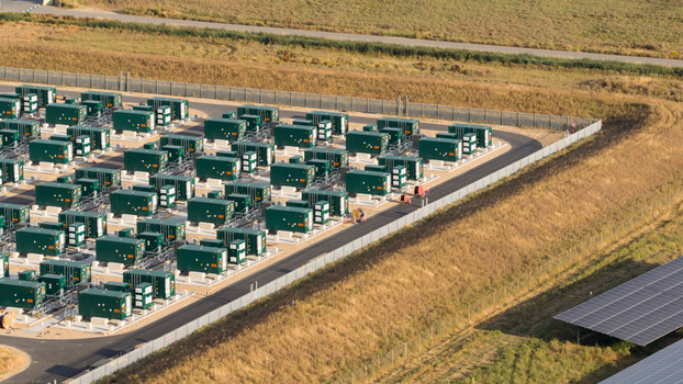 Aerial view of a battery energy storage system facility with rows of green containerized battery units gravel ground and perimeter fencing in London England United Kingdom.