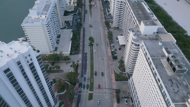 Aerial view of tall white apartment buildings and palm trees lining the road with traffic in Miami Beach Florida United States. Aerial view of tall white apartment buildings and palm trees lining the road with traffic in Miami Beach Florida United States.