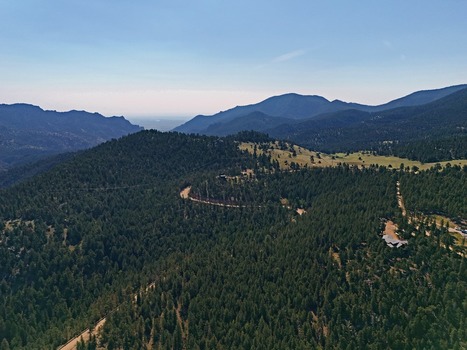 Aerial view of Crescent Meadows Trailhead surrounded by dense pine forests and rolling mountain terrain under a clear blue sky in Golden Colorado United States. Aerial view of Crescent Meadows Trailhead surrounded by dense pine forests and rolling mountain terrain under a clear blue sky in Golden Colorado United States.