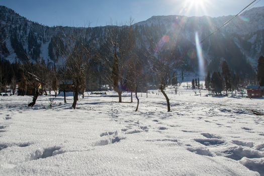 View of Arang Kel village covered in deep snow with bare trees and towering mountains under a bright sun in Arang Kel Kashmir Pakistan. View of Arang Kel village covered in deep snow with bare trees and towering mountains under a bright sun in Arang Kel Kashmir Pakistan.
