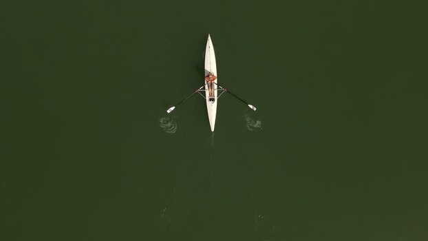 Aerial view of a person rowing a white scull boat France. Aerial view of a person rowing a white scull boat France.