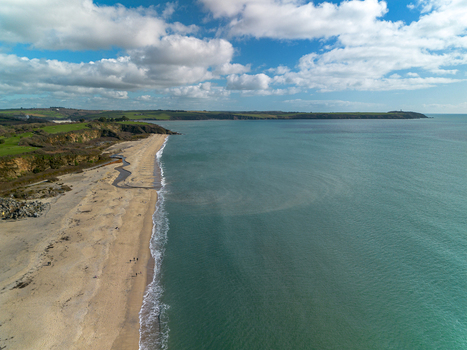 Aerial view of the sandy beach and turquoise waters of Carlyon Bay with dramatic cliffs and green coastal fields in Carlyon Bay Cornwall United Kingdom. Aerial view of the sandy beach and turquoise waters of Carlyon Bay with dramatic cliffs and green coastal fields in Carlyon Bay Cornwall United Kingdom.