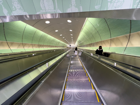 View of the long escalators at Grand Central Madison with people descending between green curved walls in New York New York United States. View of the long escalators at Grand Central Madison with people descending between green curved walls in New York New York United States.