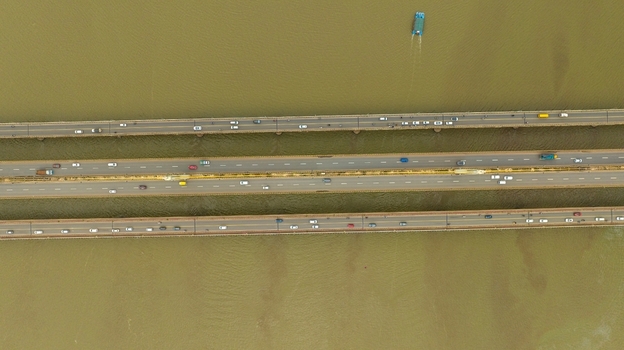 Aerial view of Atal Setu bridge spanning the Mandovi River with flowing traffic and a small boat navigating the water in Panaji Goa India.