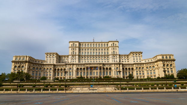 View of the massive neoclassical Palace of the Parliament building featuring grand architecture a symmetrical facade and manicured green terraces in Bucharest Bucharest Romania.