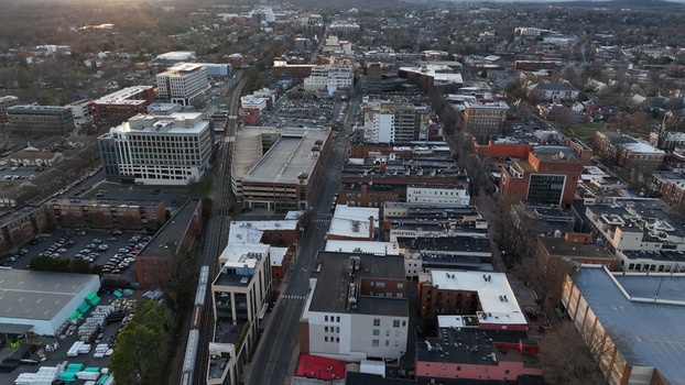 Aerial view of the urban landscape at sunset featuring buildings streets and a railway line running through the downtown area in Charlottesville Virginia United States.