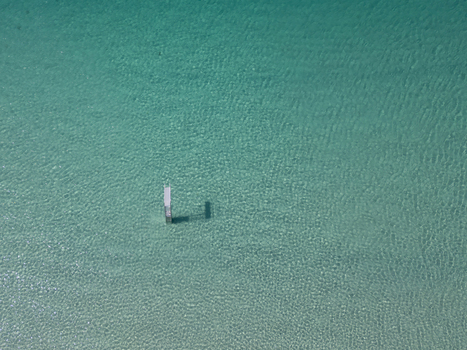 Aerial view of clear turquoise water with a white ladder structure casting a shadow on the sandy seabed in Trebeurden Brittany France. Aerial view of clear turquoise water with a white ladder structure casting a shadow on the sandy seabed in Trebeurden Brittany France.
