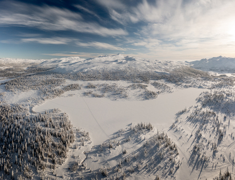 Aerial view of Gaustablikk Fjellresort surrounded by snow covered forests and a frozen lake under a bright winter sky in Rjukan Telemark Norway. Aerial view of Gaustablikk Fjellresort surrounded by snow covered forests and a frozen lake under a bright winter sky in Rjukan Telemark Norway.