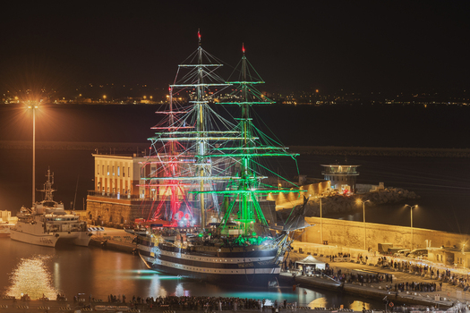 Ancona Italy 12 October 2022 Aerial view of the Amerigo Vespucci tall ship illuminated with the colors of the Italian flag at night in the port of Ancona with crowds gathered on the pier. Ancona Italy 12 October 2022 Aerial view of the Amerigo Vespucci tall ship illuminated with the colors of the Italian flag at night in the port of Ancona with crowds gathered on the pier.