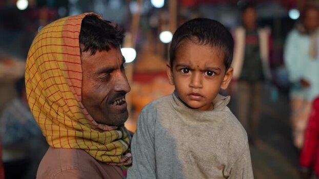 View of a man holding a young child at a night market Bangladesh.
