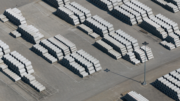 Aerial view of neatly stacked large concrete pipes arranged in rows across an industrial storage yard under bright daylight Oosterhout North Brabant Netherlands. Aerial view of neatly stacked large concrete pipes arranged in rows across an industrial storage yard under bright daylight Oosterhout North Brabant Netherlands.