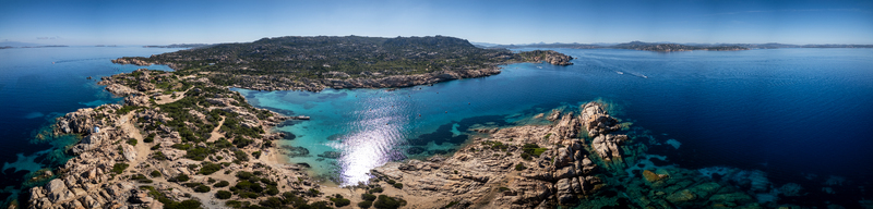 Aerial view of the Carlotto coastline featuring rocky cliffs turquoise bays and Mediterranean scrub under a clear blue sky in La Maddalena Sardinia Italy. Aerial view of the Carlotto coastline featuring rocky cliffs turquoise bays and Mediterranean scrub under a clear blue sky in La Maddalena Sardinia Italy.