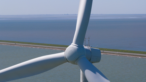 Aerial view of Windpark Fryslan wind turbine blades rotating above the IJsselmeer with a causeway and water in the background Breezanddijk Friesland Netherlands. Aerial view of Windpark Fryslan wind turbine blades rotating above the IJsselmeer with a causeway and water in the background Breezanddijk Friesland Netherlands.