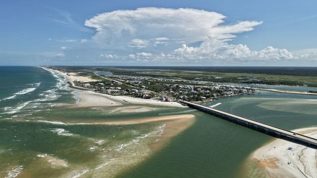 Aerial view of Matanzas Inlet featuring its bridge sandy coastline and turquoise waters under a bright blue sky in St. Johns County Florida United States. Aerial view of Matanzas Inlet featuring its bridge sandy coastline and turquoise waters under a bright blue sky in St. Johns County Florida United States.