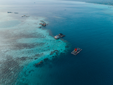 Aerial view of fish cages floating in the turquoise waters of a coral reef in Karimunjawa Jawa Tengah Indonesia. Aerial view of fish cages floating in the turquoise waters of a coral reef in Karimunjawa Jawa Tengah Indonesia.