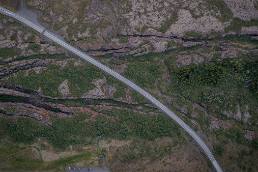 Aerial view of Thingvellir National Park showing a road winding through rugged volcanic fissures and green mossy terrain in Selfoss Blaskogabyggd Iceland. Aerial view of Thingvellir National Park showing a road winding through rugged volcanic fissures and green mossy terrain in Selfoss Blaskogabyggd Iceland.