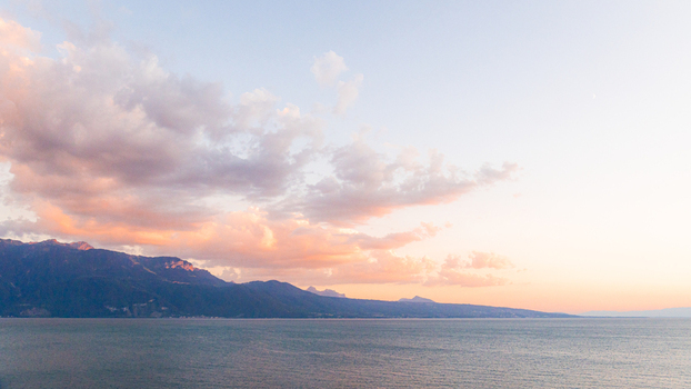 View of the sunset over Lake Geneva with mountains in the background in Bourg en Lavaux Vaud Switzerland. View of the sunset over Lake Geneva with mountains in the background in Bourg en Lavaux Vaud Switzerland.