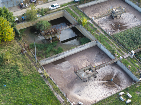 Aerial view of a wastewater treatment plant featuring aeration tanks with industrial machinery and surrounding green vegetation in Krakow Lesser Poland Voivode Poland.
