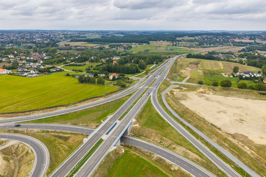 Aerial view of a highway interchange surrounded by green fields and rural houses in Gdansk Pomeranian Voivodeship Poland. Aerial view of a highway interchange surrounded by green fields and rural houses in Gdansk Pomeranian Voivodeship Poland.