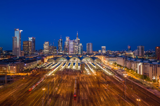 Aerial view of Hauptbahnhof central station with illuminated tracks and the modern city skyline at twilight in Frankfurt am Main Hessen Germany.