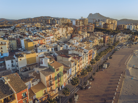 Aerial view of colorful houses along the promenade and sandy beach with palm trees under a clear sky and distant mountains La Vila Joiosa Valencian Community Spain. Aerial view of colorful houses along the promenade and sandy beach with palm trees under a clear sky and distant mountains La Vila Joiosa Valencian Community Spain.