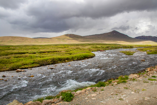 View of a flowing river through the green plains of Deosai National Park under a dramatic cloudy sky in Skardu Gilgit Pakistan. View of a flowing river through the green plains of Deosai National Park under a dramatic cloudy sky in Skardu Gilgit Pakistan.