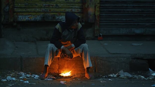 View of a man warming himself by a fire at night in Bogura Bangladesh. View of a man warming himself by a fire at night in Bogura Bangladesh.