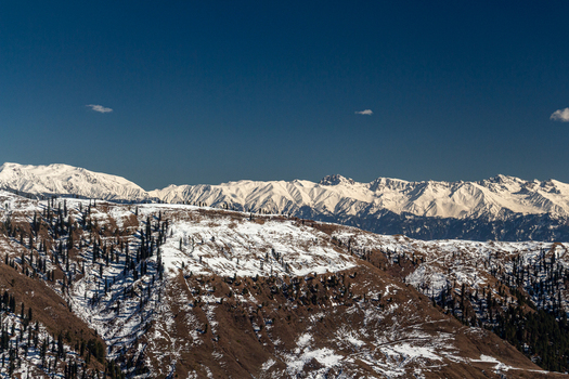 View of snow dusted mountains under a clear blue sky create a serene winter landscape the peaks contrasting with the dark slopes Lasdana Azad Kashmir Pakistan.