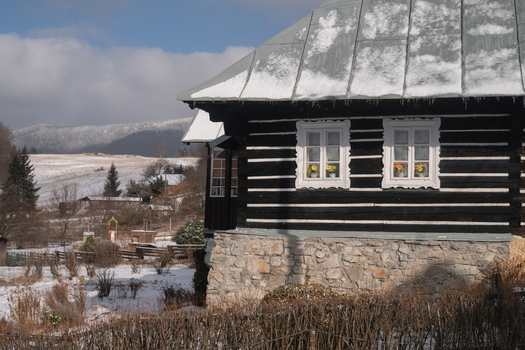 View of a traditional dark wooden house with snow dusted roof and intricate window frames nestled in a snowy landscape Donovaly Banskobystricky kraj Slovakia. View of a traditional dark wooden house with snow dusted roof and intricate window frames nestled in a snowy landscape Donovaly Banskobystricky kraj Slovakia.