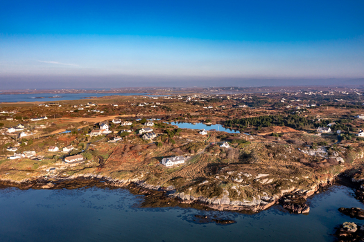 Aerial view of the coastal landscape featuring scattered houses rocky terrain and small lakes along the rugged coastline in Cloughglass County Donegal Ireland. Aerial view of the coastal landscape featuring scattered houses rocky terrain and small lakes along the rugged coastline in Cloughglass County Donegal Ireland.
