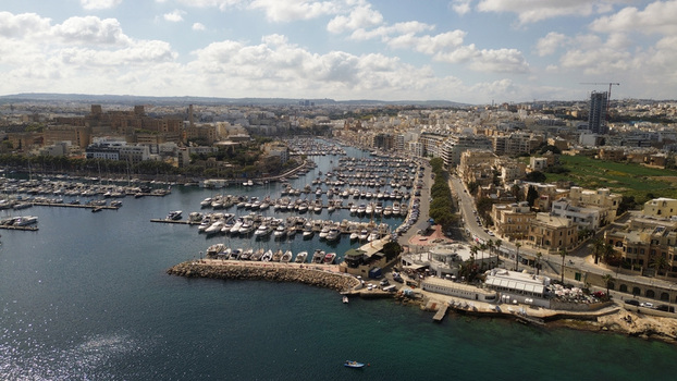 Aerial view of the Msida Marina with numerous yachts and boats docked in the harbor surrounded by urban architecture and coastal roads in Valletta Port Region Malta. Aerial view of the Msida Marina with numerous yachts and boats docked in the harbor surrounded by urban architecture and coastal roads in Valletta Port Region Malta.