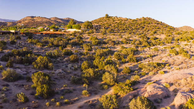 Aerial view of desert landscape with sparse shrubs rolling hills and residential houses in the distance in the United States. Aerial view of desert landscape with sparse shrubs rolling hills and residential houses in the distance in the United States.