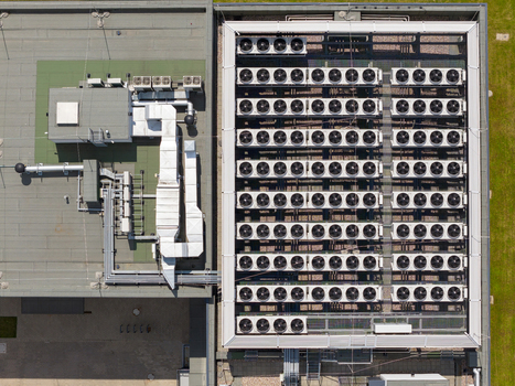 Aerial view of an AI data center featuring a large array of industrial cooling fans and ventilation ducts on a flat rooftop Warsaw Masovian Voivodeship Poland. Aerial view of an AI data center featuring a large array of industrial cooling fans and ventilation ducts on a flat rooftop Warsaw Masovian Voivodeship Poland.