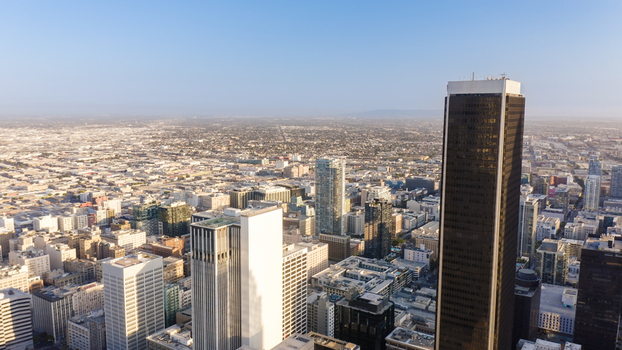 Aerial view of the Los Angeles skyline featuring modern skyscrapers dense urban architecture and distant hills under a clear sky in Los Angeles California United States.