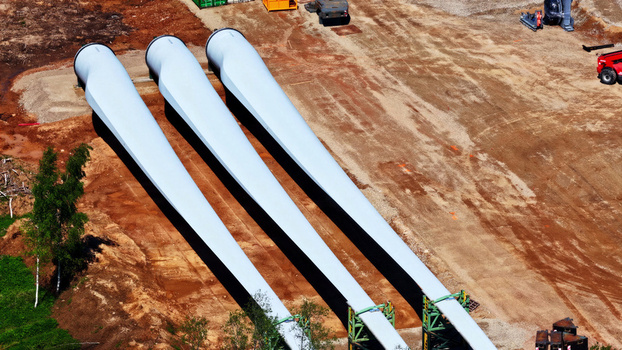 Aerial view of three large white wind turbine blades resting on the ground at a construction site in Latvia. Aerial view of three large white wind turbine blades resting on the ground at a construction site in Latvia.