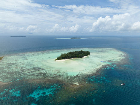Aerial view of the vibrant turquoise waters encircling Cemara Kecil Island contrasting with the deep blues of the open sea Karimunjawa Central Java Indonesia.