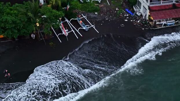 Aerial view of black sand beach with traditional boats Indonesia.