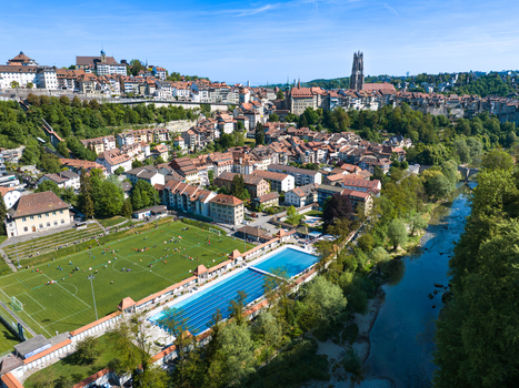 Aerial view of the St Nicolas Cathedral and the historic old town with the Piscine de la Motta and a football field by the Sarine river in Fribourg Fribourg Switzerland. Aerial view of the St Nicolas Cathedral and the historic old town with the Piscine de la Motta and a football field by the Sarine river in Fribourg Fribourg Switzerland.