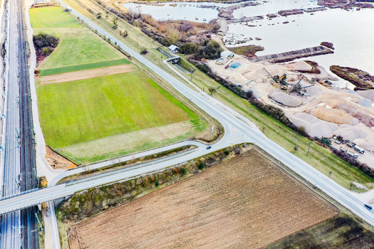Aerial view of a railway line running alongside a road bridge agricultural fields and a gravel quarry with industrial machinery Forchheim Bavaria Germany. Aerial view of a railway line running alongside a road bridge agricultural fields and a gravel quarry with industrial machinery Forchheim Bavaria Germany.
